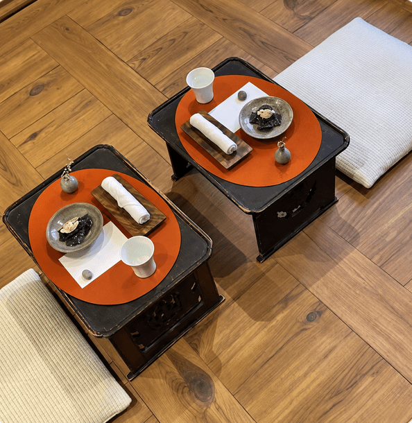 Two low tables set for a tea ceremony on a wooden floor.