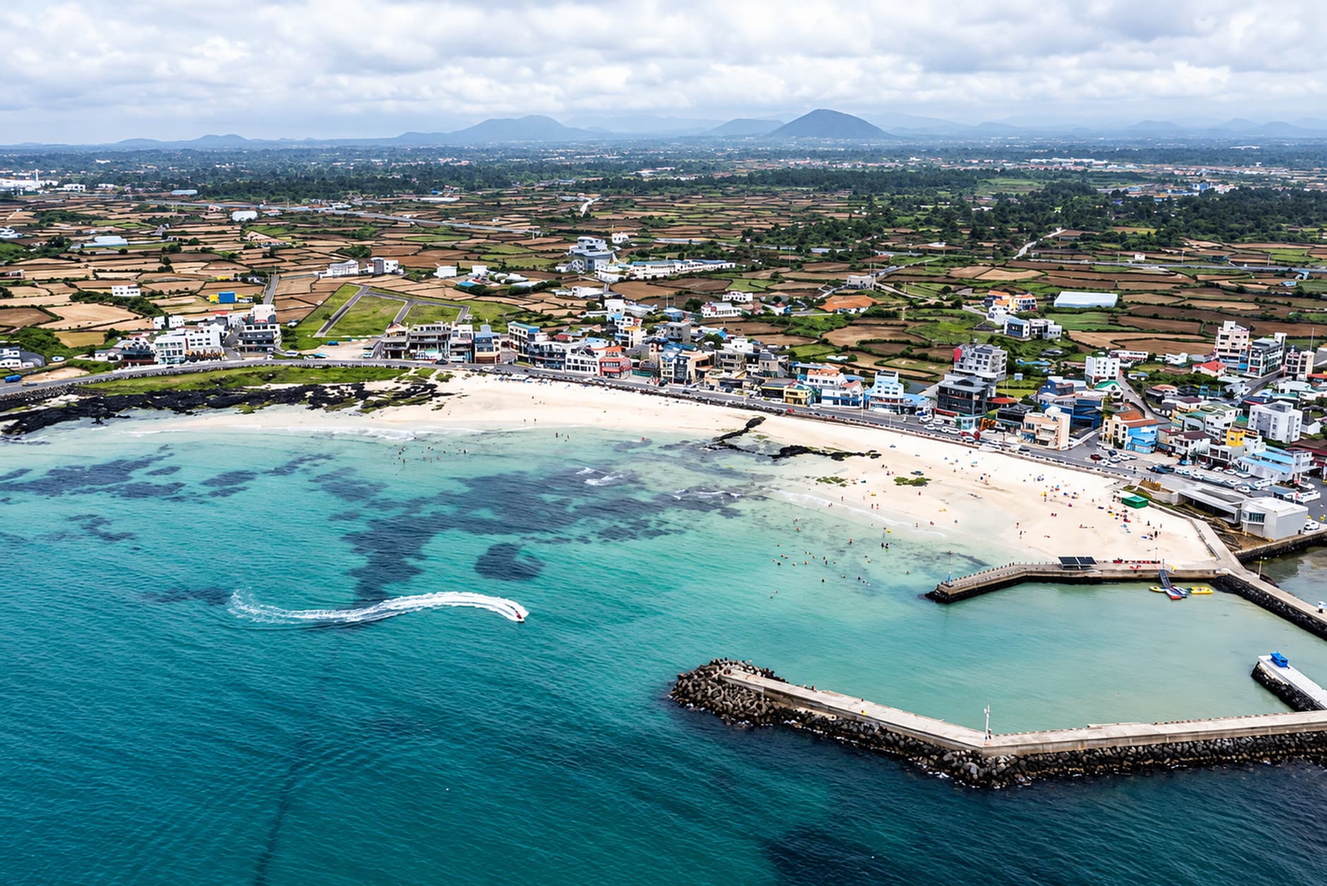 The pale sand and shallow water of Woljeongri Beach on Jeju Island.